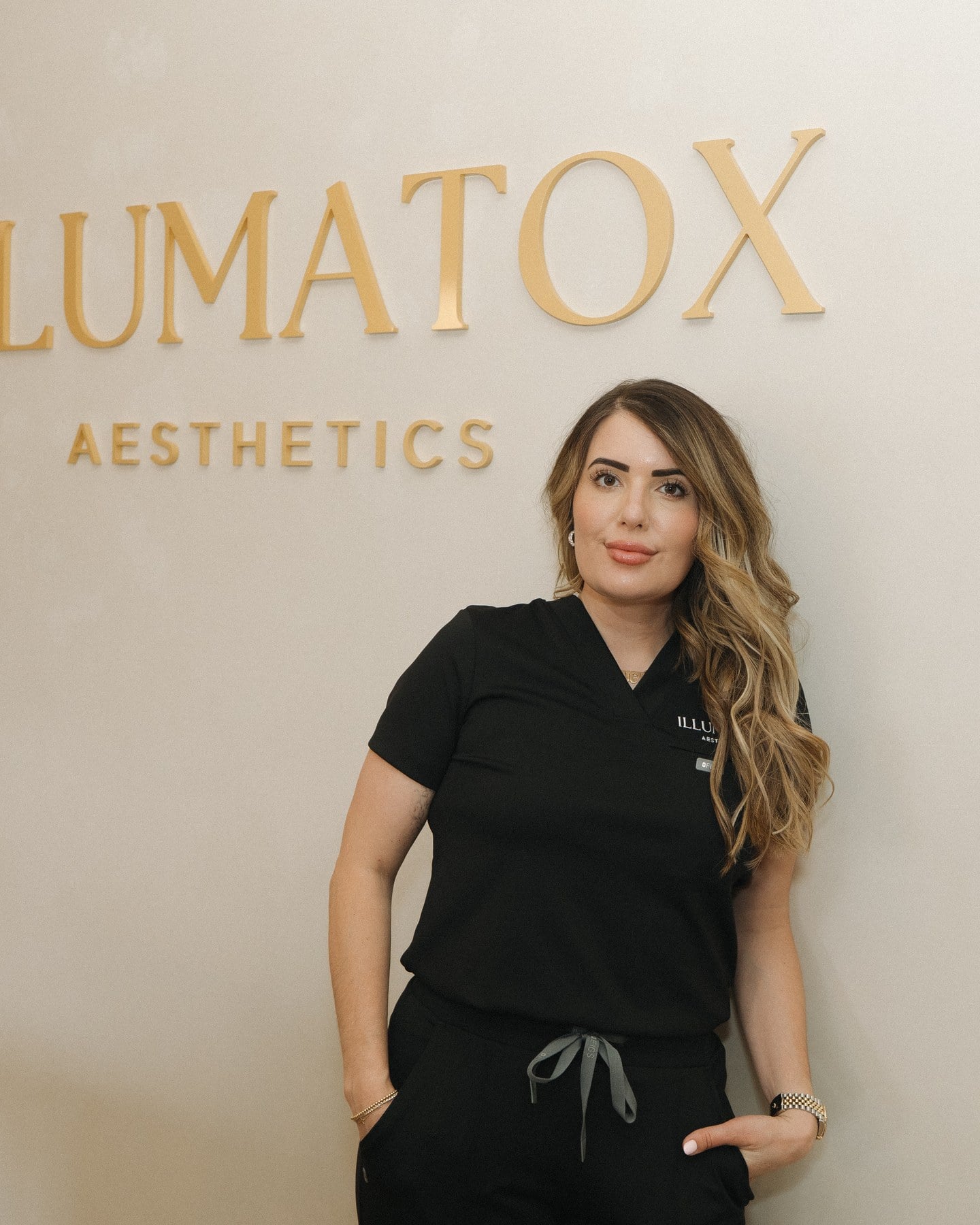 Elizabeth Coenen, APNP, FNP-BC, standing beneath the gold Illumatox lettering in the Neenah studio she founded