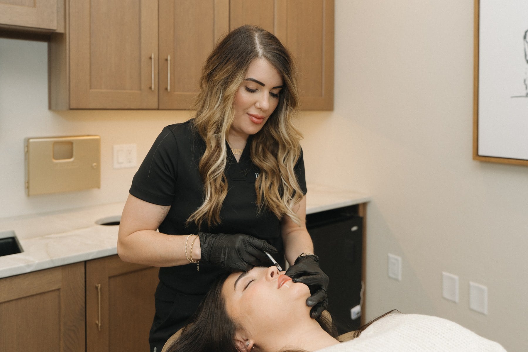 An injector preparing treatment beneath the chin of a reclined client at Illumatox in Neenah